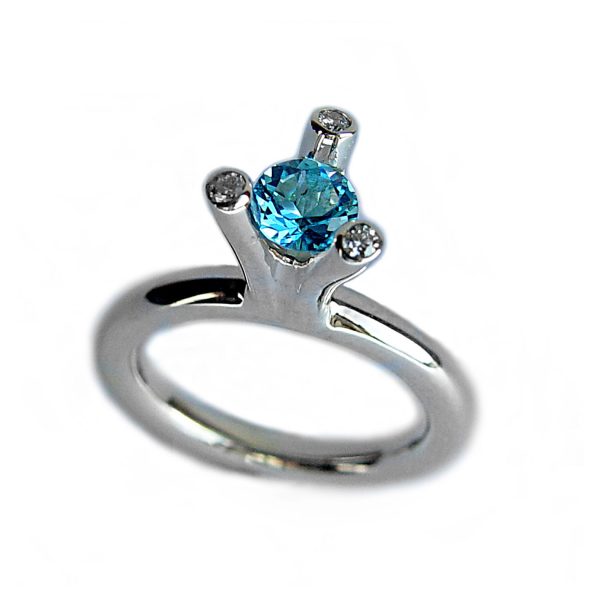 The 3 branch bough ring is bold and majestic in design and is inspired by nature. The silver ring has a comfortable rounded shank of 3mm and the setting consists of a 5mm gemstone encircled by 3x 0.02ct diamonds (height of setting when worn is approx 8mm). The featured image shows a 5mm blue topaz. The ring comes with a variety of gemstones for example amethyst, iolite, citrine, peridot & garnet.