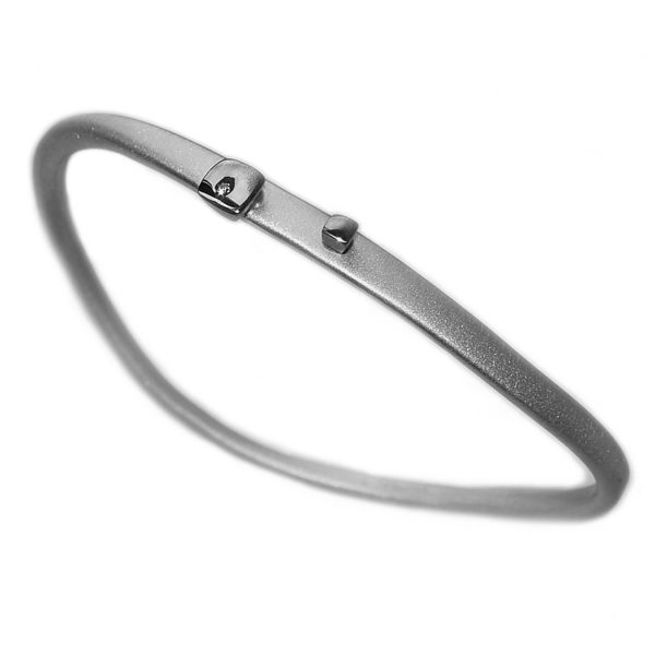 This striking silver diamond bangle has silver detail and is set with a single sparkling diamond (0.02ct vsfg). The solid silver bangle is hand forged from round wire which creates its unusual & unique shape. it is approx 4mm wide at the top.  Each bangle is individually handmade to order and can be made in a range of sizes. It comes in an all satin finish, or in a satin finish with polished silver detail (as featured).