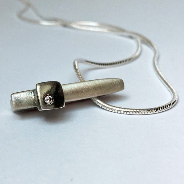 Solid silver ingot with silver detail set with solitary sparkling diamond (0.02ct vsfg). Approximate dimensions are length 24mm, width 4mm, depth 5mm. The pendant comes on a silver snake chain. 