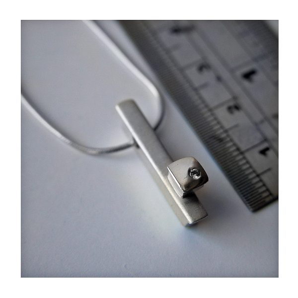 Solid silver ingot with silver detail set with solitary sparkling diamond (0.02ct vsfg). Approximate dimensions are length 24mm, width 4mm, depth 5mm. The pendant comes on a silver snake chain. 