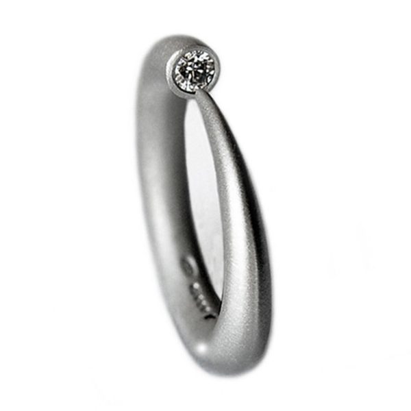 Hand forged silver tapering contemporary ring with a comfortable rounded band. The solid sterling silver band tapers to a point from 4mm and is end set with a brilliant  0.1ct vsfg diamond. The ring is one of the original designs in Paul’s timeless classic ”wiggly ” collection. This minimalist ring is practical and suitable for everyday wear or special occasions. It also makes the perfect engagement ring and can be paired with 4mm halo wedding ring C19. Platinum, 9ct/18ct white gold, 9ct/18ct yellow gold versions are available on request – please contact for further details.