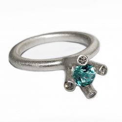 The 4 branch bough ring is bold and majestic in design and is inspired by nature. The silver ring has a comfortable rounded band of 3mm and the setting consists of a 5mm gemstone encircled by 4x 0.02ct diamonds (height of setting when worn is approx 8mm). The featured image shows a 5mm blue topaz. The ring comes with a variety of gemstones for example amethyst, iolite, citrine, peridot & garnet.