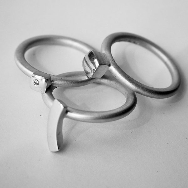This solid silver diamond ring set 9 consists of three unique rings. Each ring is 2.5mm round with a comfortable rounded shank (maximum width of the ring set is 7.5mm). Each ring has silver detailing, and one ring is set with a single diamond (0.02vsfg). The ring set is also available with 18ct gold detailing or in an all 18ct yellow gold version. The rings can also be bought individually on request.
