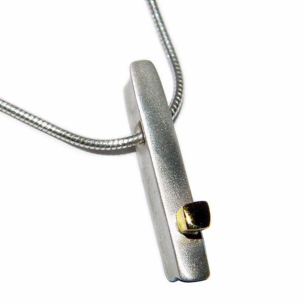 This silver ingot necklace has contrasting small 18ct yellow gold detail. It has approximate dimensions of length 24mm, width 4mm, depth 5mm and comes on a silver snake chain. (It is also possible in an all silver version). The solid silver necklace is perfect for everyday wear or special occasions.