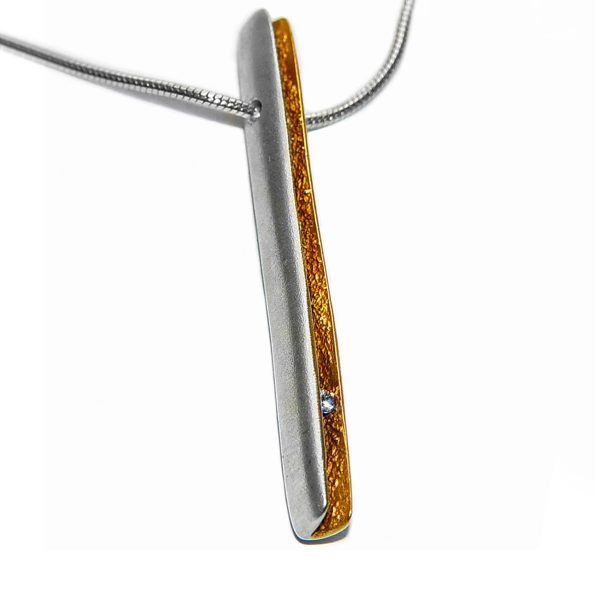 Contemporary shell diamond pendant.This elegant rectangular silver pendant has a sparkling 3pt (0.03ct) vsfg diamond. It also has a rich 22ct gold plated textured interior. It is approximately 46mm long, 4.6mm wide and has a depth 5.75mm. The pendant usually comes in a satin finish on a silver snake chain.