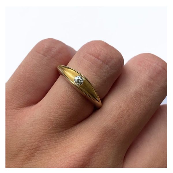 The 18ct yellow gold diamond shell ring is an elegant and unusual sculptural ring. The 10pt diamond is set to allow maximum light around the stone. The ring has a lovely smooth organic shape. The comfortable solid band is split across the top to reveal a sparkling 0.1ct diamond trapped within the gold interior. An unusual statement ring which is also makes the perfect engagement ring. Brilliant 0.1ct vsfg diamond tension set in satin finished 18ct yellow gold. Dimensions are 5mm wide & 5mm depth.