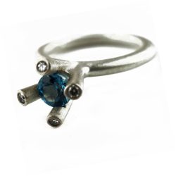 The 4 branch bough ring is bold and majestic in design and is inspired by nature. The silver ring has a comfortable rounded band of 3mm and the setting consists of a 5mm gemstone encircled by 4x 0.02ct diamonds (height of setting when worn is approx 8mm). The featured image shows a 5mm blue topaz. The ring comes with a variety of gemstones for example amethyst, iolite, citrine, peridot & garnet & cz.
